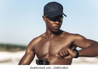 Muscular black man uses a fitness tracker to track progress, heart rate and calories burned during a workout. Portrait of an athlete checking the pulse with a digital watch - Powered by Shutterstock