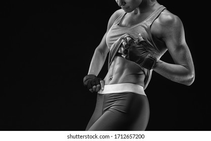 Muscular body, abs over black background. Black and white close-up horizontal portrait of fitness woman in sports clothing tank top. Copy free space on left