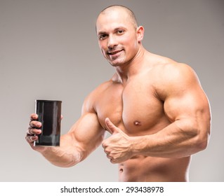 Muscular Bodybuilder Drinking Protein On A Dark Background.