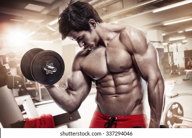 Muscular Bodybuilder Guy Doing Exercises With Dumbbells In Gym
