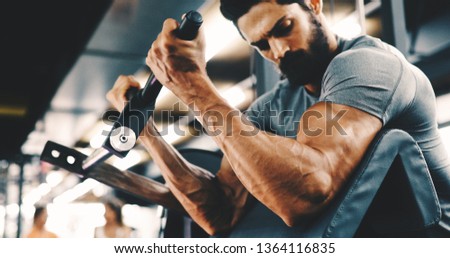 Muscular bodybuilder guy doing exercises in gym