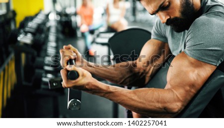 Muscular bodybuilder guy doing exercises in gym