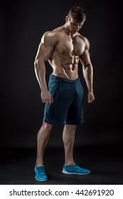 Muscular bodybuilder guy doing posing over black background