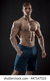 Muscular bodybuilder guy doing posing over black background