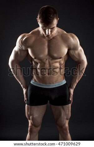 Muscular bodybuilder guy doing posing over black background