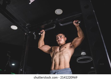 A Muscular And Buff Asian Guy Trains His Back At The Gym. Doing A Set Of Pull-ups. Shirtless Revealing His Ripped Physique.