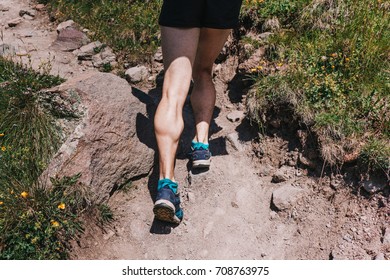 Muscular calves of a young athlete running up a mountain path, ultramarathon and skyranning