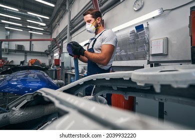 Muscular Car Technician Pulling Off Abrasive Paper From Grinder