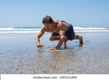 Muscular Caucasian Man Doing Bear Crawl Workout On Sandy Beach On Sunny Day At Lowtide