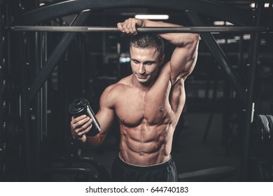 Muscular Caucasian Man On Diet Resting After Exercise And Drinking Protein Powder From Shaker In The Gym