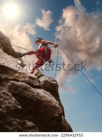 Muscular climber man in protective helmet abseiling from cliff rock wall using rope Belay device and climbing harness on evening sunset sky background. Active extreme sports time spending concept. [[stock_photo]] © 