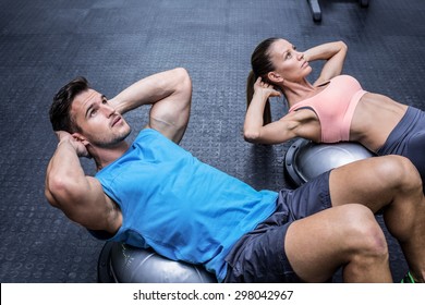 Muscular couple doing abdominal crunch on a bosu ball