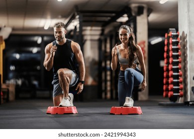 A muscular couple in shape is exercising gluteus and legs in a gym.