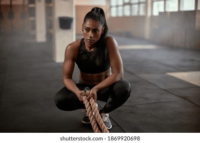 Muscular Ethnic Female Athlete In Black Sportswear Looking Away And Thinking While Resting After Intense Exercise With Rope During Fitness Training