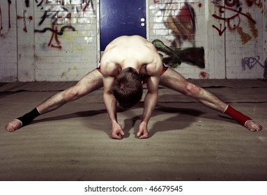 Muscular fighter doing press-ups in a suburban basement