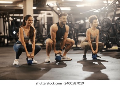 Muscular fit friends doing kettle bell squats in a gym. Gym workout. Friends working out at gym. - Powered by Shutterstock