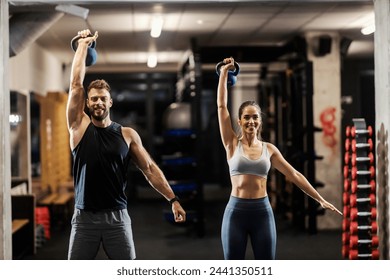 Muscular fit friends standing in a gym and lifting kettle bells. - Powered by Shutterstock