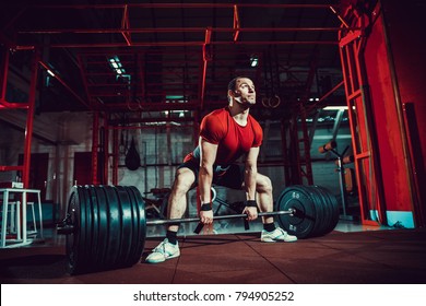 Muscular fitness man doing deadlift a barbell in modern fitness center. Functional training. Snatch exercise. Sumo style.
