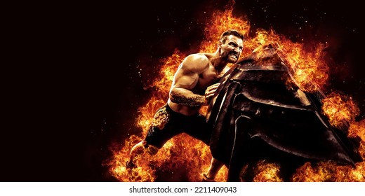 Muscular fitness shirtless man moving large tire in flames, concept lifting, workout cross training.  - Shutterstock ID 2211409043