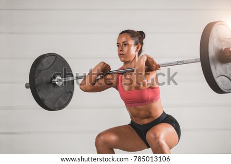 Muscular fitness woman deadlift a barbell over his head in the gym. Sports, cross fit and fitness - concept of healthy lifestyle. Woman in the fitness club. 
