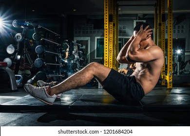 Muscular guy doing sit ups at gym with other people in background. Young athlete doing stomach workout in modern gym. Handsome fit man doing crunches at gym. - Shutterstock ID 1201684204