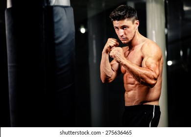 Muscular Handsome Man Fighter With Boxing Bag In Gym