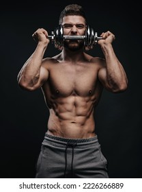 Muscular hunk with dumbbell posing in studio. Fitness male model holding gym equipment. Shirtless man at black background. - Shutterstock ID 2226266889