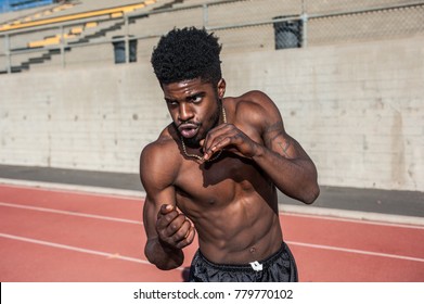 Muscular Jamaican boxer in defensive stance while shadowboxing on stadium track. - Powered by Shutterstock