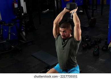 Muscular Latino Man Doing Exercises For Biceps Sitting On A Gym Bench