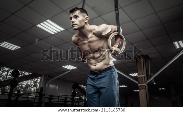 Muscular male gymnast
exercising on gymnastic rings in a modern health club. Healthy
lifestyle concept
