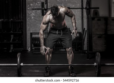 muscular man in about to pickup barbell  - Powered by Shutterstock