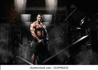 Muscular man bodybuilder training in gym and posing. Fit muscle guy workout with weights and barbell