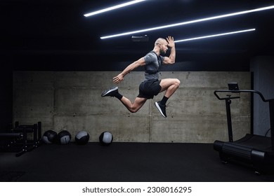 A muscular man captured in air as he jumps in a modern gym, showcasing his athleticism, power, and determination through a highintensity fitness routine