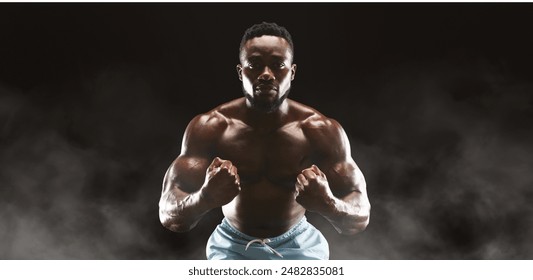 A muscular man with a determined expression poses against a dark background with smoke swirling around him. - Powered by Shutterstock