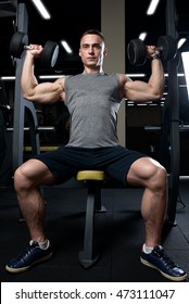 Muscular Man Doing Dumbbell Overhead Press In The Gym