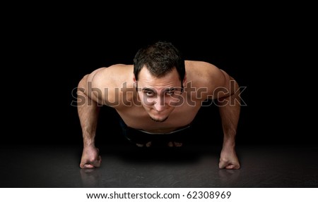 Muscular man doing push up exercise. Black background in studio.