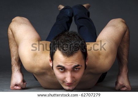 Muscular man doing push up exercise, grey background in studio.