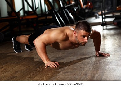 Muscular man doing a push-ups at gym. - Powered by Shutterstock