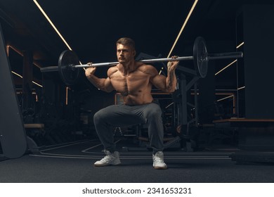 Muscular man doing squats with barbell in a gym. Male bodybuilder doing workout Confident young man doing barbell workout in gym Powerful attractive man. - Powered by Shutterstock