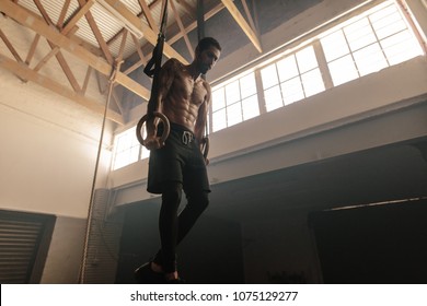 Muscular man doing workout with rings. Fit young woman exercising with gymnastic rings fitness club. - Powered by Shutterstock