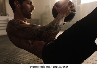 Muscular man exercise with medicine ball at health club. Fitness routine with exercise ball to maintain the abs. - Powered by Shutterstock