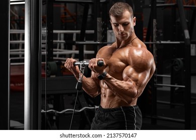Muscular man in gym doing exercises for biceps, working out. Strong male naked torso abs
