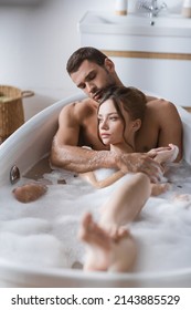 Muscular Man Hugging Girlfriend In Bathtub With Foam At Home