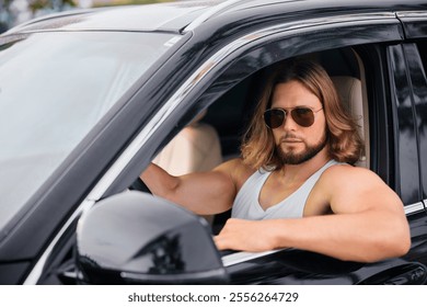 A muscular man with long hair and sunglasses sitting in a sleek black car The focus is on his confident expression against the elegant interior - Powered by Shutterstock