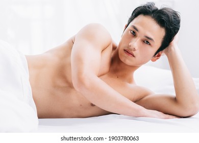The muscular man is lying on the bed
