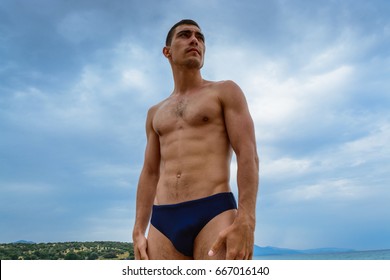 Muscular man standing on the beach in a swimming trunks. The concept of freedom, power, sport, healthy lifestyle