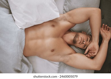 Muscular man and stretching arms in bed for rest, relax and sleep at home on weekend from above. Male person or model with strong body on pillow and blankets for comfort, peace and recovery portrait - Powered by Shutterstock