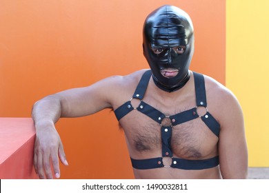 Muscular man wearing leather harness and latex mask 