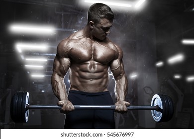 Muscular Man Workout With Barbell At Gym. Brutal Bodybuilder Athletic Man With Perfect Abs, Shoulders, Biceps, Triceps And Chest. Dead Lift Barbells Workout