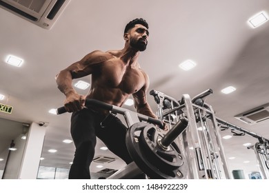 Muscular men exercising with weights. He is performing T bar rows for back muscle / Bodybuilder in the gym - Powered by Shutterstock